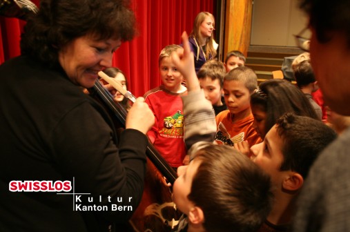 Kinder befragen Musikerin. Enfants posant des questions au musicien. I bambini rivolgono domande alla musicista.