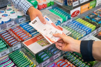 Primo piano del personale di vendita che consegna al cliente la schedina Swiss Lotto e lo scontrino. 